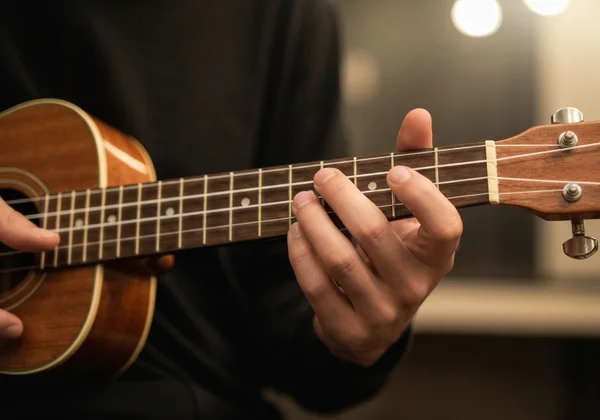 Hand playing C Major chord on a ukulele with chord chart