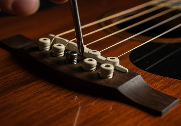 Close-up of guitar bridge, saddle being adjusted for intonation