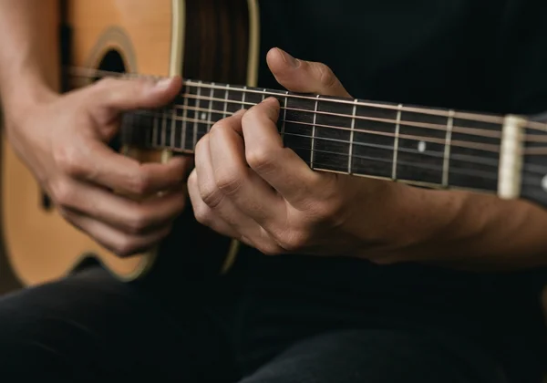 User tuning guitar with online tuner on laptop screen