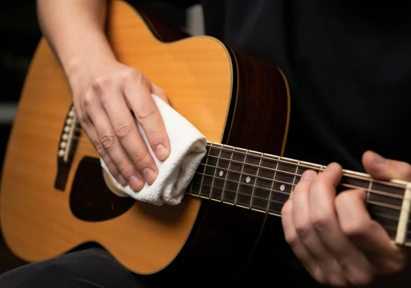 Close-up of hands wiping guitar strings